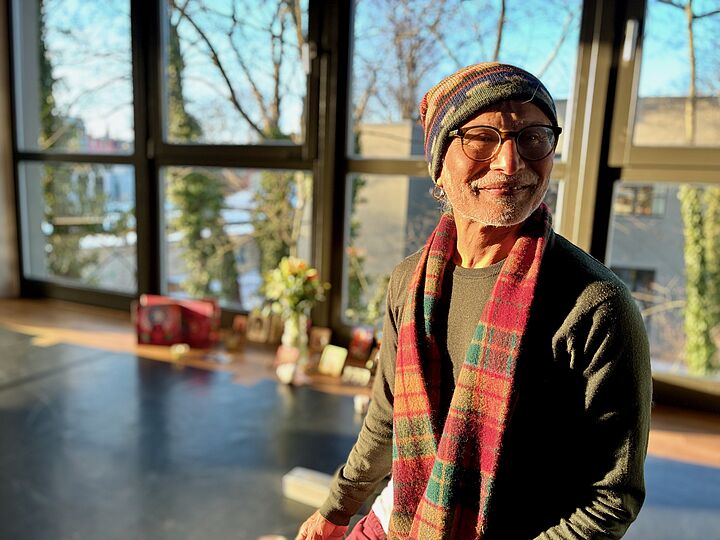 Yogalehrer Michael Stewart mit Mütze und buntem Schal im sonnigen Seminarraum